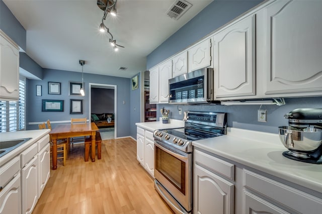 4500 Keys Dr, The Colony, TX 75056 - kitchen featuring appliances with stainless steel finishes, white cabinetry, light wood-style flooring, light countertops, and hanging light fixtures