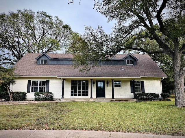 1707 Williamsburg Cir, Ennis, TX 75119 - view of front facade with a front lawn, covered porch, a shingled roof, and brick siding