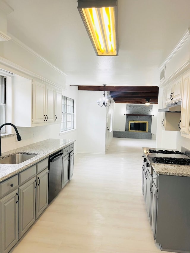 1707 Williamsburg Cir, Ennis, TX 75119 - kitchen featuring dishwasher, a sink, light stone countertops, light wood-style flooring, and a fireplace