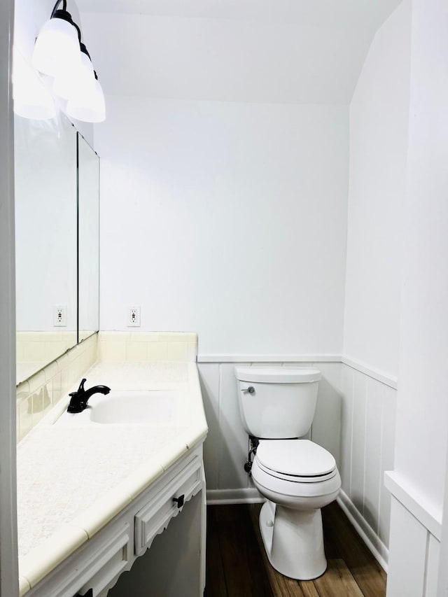 1707 Williamsburg Cir, Ennis, TX 75119 - half bathroom with vanity, wainscoting, wood finished floors, and toilet