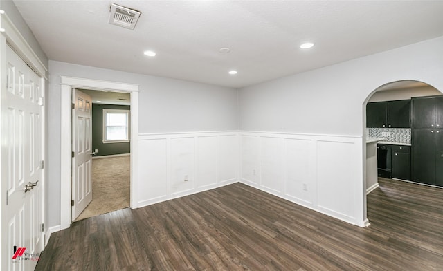 9472 Ranch Ln, Shreveport, LA 71106 - empty room with dark wood-type flooring, arched walkways, a wainscoted wall, and recessed lighting