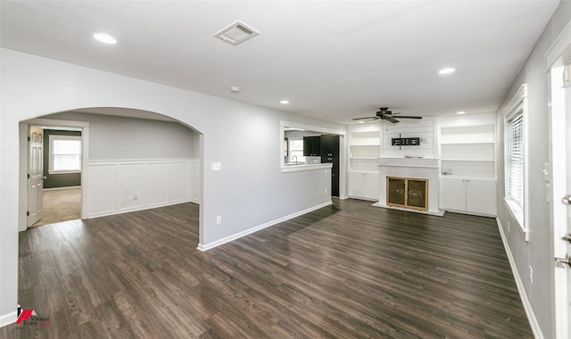 9472 Ranch Ln, Shreveport, LA 71106 - unfurnished living room with a ceiling fan, arched walkways, dark wood-style floors, a large fireplace, and healthy amount of natural light