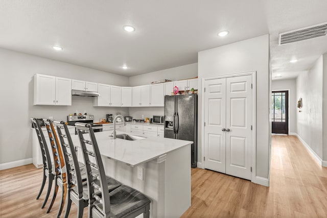 402 Robbins St, Cleburne, TX 76031 - kitchen featuring a sink, black fridge, stainless steel range with electric cooktop, light wood-style floors, and recessed lighting