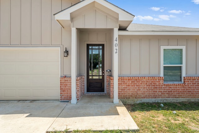 402 Robbins St, Cleburne, TX 76031 - property entrance featuring a garage, board and batten siding, brick siding, driveway, and roof with shingles