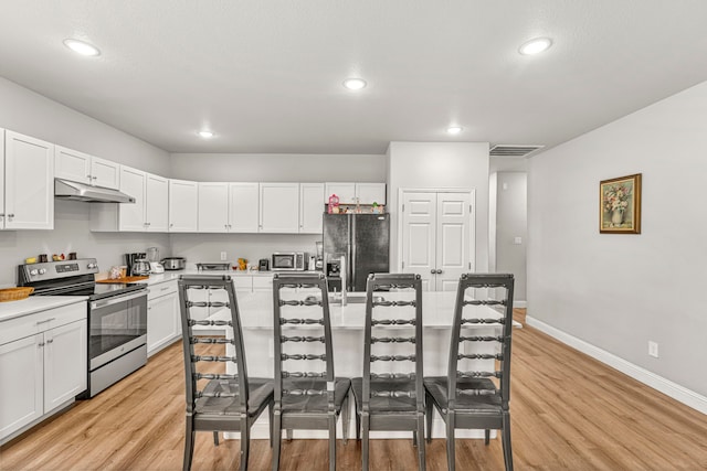 402 Robbins St, Cleburne, TX 76031 - kitchen with electric range, black refrigerator with ice dispenser, under cabinet range hood, a breakfast bar, and baseboards