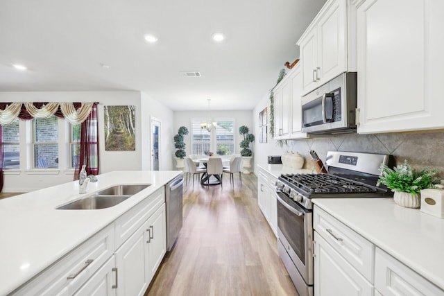 1816 Dunstan Dr, Fort Worth, TX 76052 - kitchen featuring stainless steel appliances, a sink, light wood finished floors, light countertops, and white cabinetry