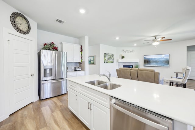 1816 Dunstan Dr, Fort Worth, TX 76052 - kitchen featuring appliances with stainless steel finishes, a sink, a fireplace, light wood-style floors, and light countertops