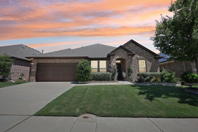 1816 Dunstan Dr, Fort Worth, TX 76052 - french country style house featuring brick siding, a garage, a yard, a shingled roof, and concrete driveway