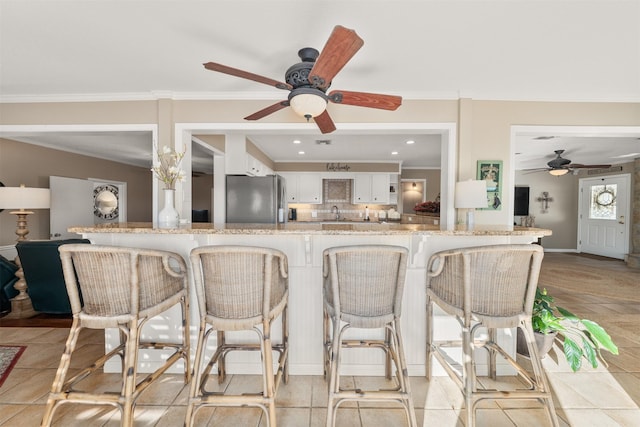 311 County Road 1710, Clifton, TX 76634 - kitchen featuring a ceiling fan, freestanding refrigerator, crown molding, a peninsula, and white cabinets