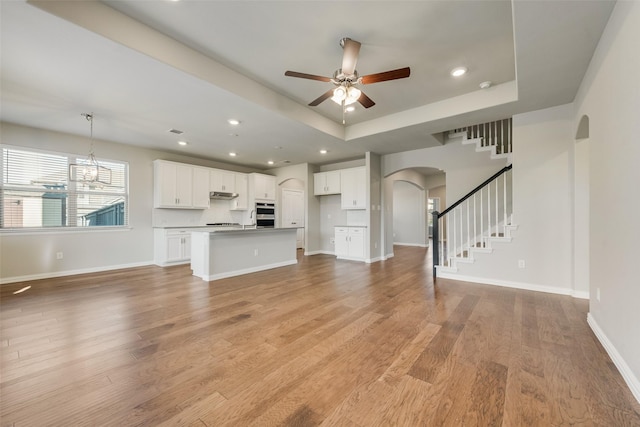 6314 Catalpa Dr, Venus, TX 76084 - unfurnished living room with arched walkways, a tray ceiling, ceiling fan, light wood-style floors, and recessed lighting