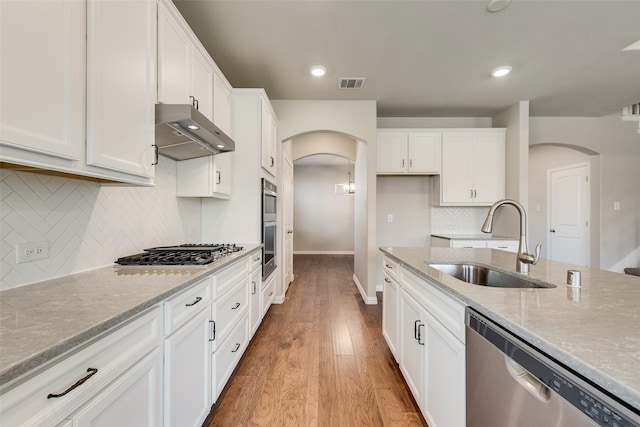 6314 Catalpa Dr, Venus, TX 76084 - kitchen with a sink, stainless steel appliances, arched walkways, wall chimney exhaust hood, and light stone countertops