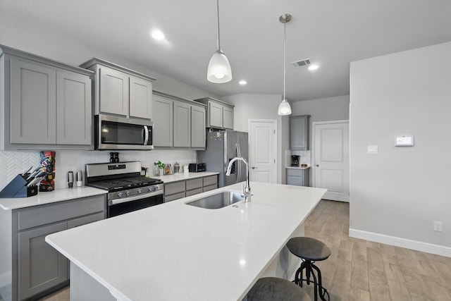 120 Texasage St, Rhome, TX 76078 - kitchen featuring appliances with stainless steel finishes, gray cabinetry, a sink, a kitchen bar, and recessed lighting