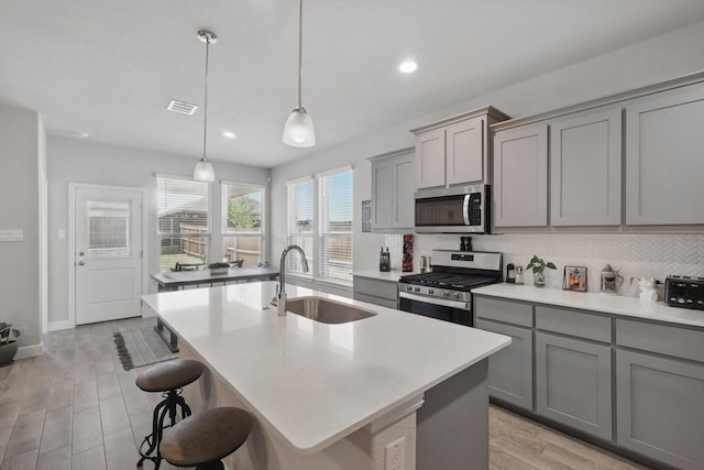 120 Texasage St, Rhome, TX 76078 - kitchen with stainless steel appliances, a sink, gray cabinetry, tasteful backsplash, and a center island with sink