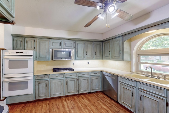 1308 Warwick St, Garland, TX 75040 - kitchen featuring appliances with stainless steel finishes, a sink, gray cabinetry, and light wood-style flooring