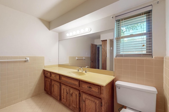 1308 Warwick St, Garland, TX 75040 - bathroom featuring tile walls, tile patterned floors, toilet, vanity, and a wainscoted wall