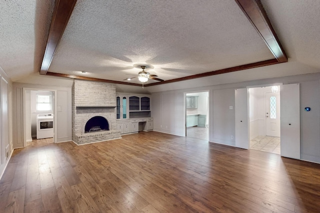 1308 Warwick St, Garland, TX 75040 - unfurnished living room featuring a textured ceiling, a ceiling fan, wood-type flooring, a fireplace, and baseboards