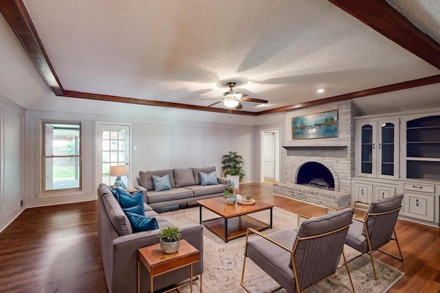 1308 Warwick St, Garland, TX 75040 - living area featuring ceiling fan, a fireplace, a decorative wall, dark wood finished floors, and ornamental molding