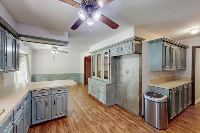1308 Warwick St, Garland, TX 75040 - kitchen with ceiling fan, a peninsula, light wood-type flooring, light countertops, and a wainscoted wall