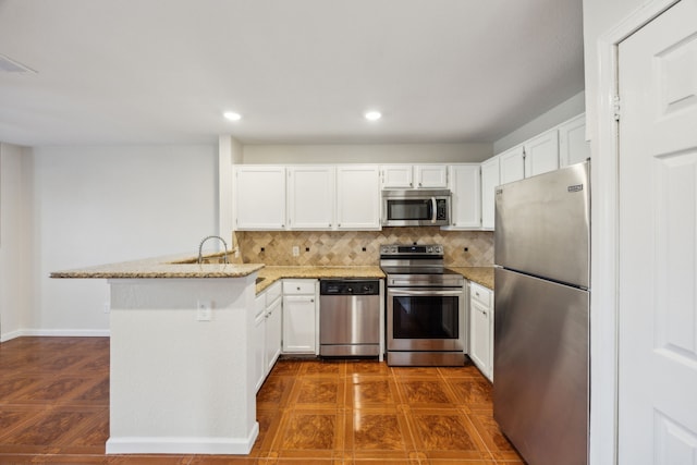 6108 Abrams Rd Unit 601, Dallas, TX 75231 - kitchen featuring stainless steel appliances, a peninsula, white cabinetry, backsplash, and recessed lighting