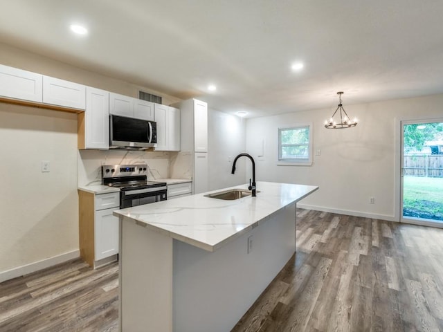 5201 Keller Cir, The Colony, TX 75056 - kitchen featuring appliances with stainless steel finishes, a sink, wood finished floors, light stone countertops, and recessed lighting