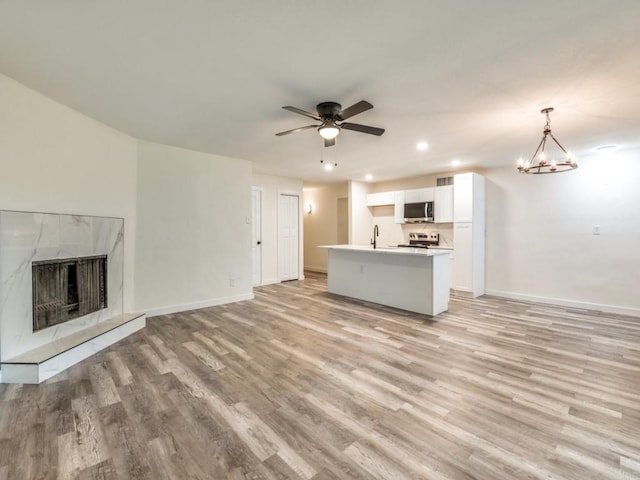 5201 Keller Cir, The Colony, TX 75056 - unfurnished living room featuring a sink, light wood-style flooring, baseboards, recessed lighting, and a tile fireplace