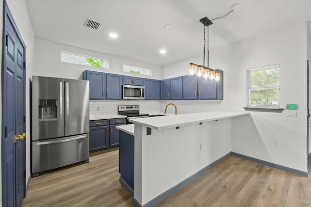 4706 Spring Ave, Dallas, TX 75210 - kitchen featuring appliances with stainless steel finishes, a peninsula, light wood-type flooring, light countertops, and recessed lighting