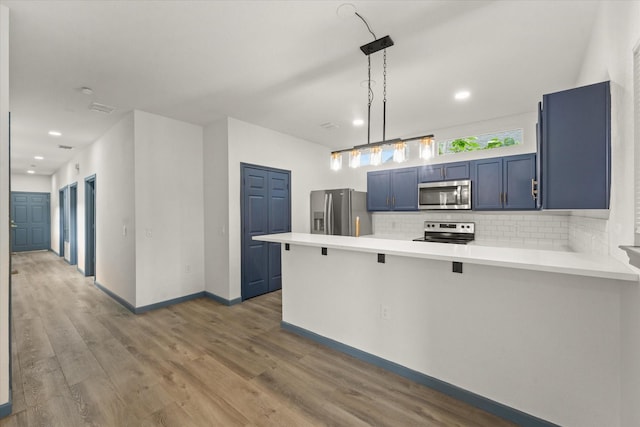 4706 Spring Ave, Dallas, TX 75210 - kitchen with appliances with stainless steel finishes, a peninsula, decorative backsplash, light countertops, and wood finished floors