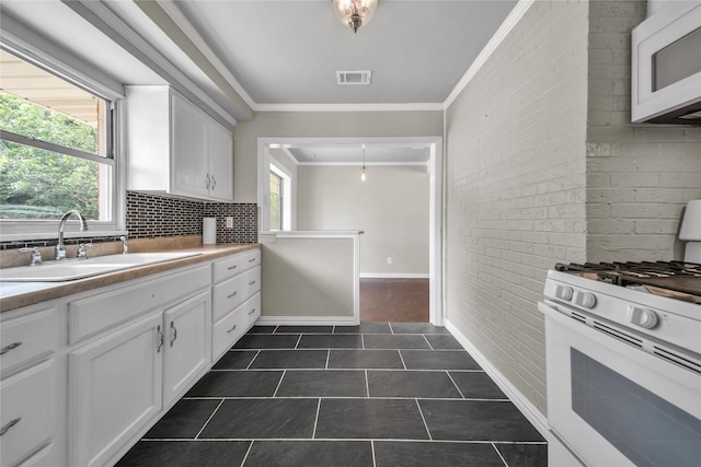 6423 Fisher Rd, Dallas, TX 75214 - kitchen with white appliances, a sink, ornamental molding, dark tile patterned flooring, and tasteful backsplash
