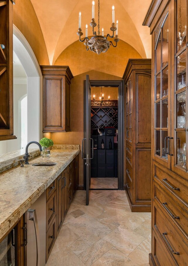 9996 Hollow Way Rd, Dallas, TX 75220 - bar area featuring a chandelier, stone tile floors, arched walkways, a sink, and hanging light fixtures
