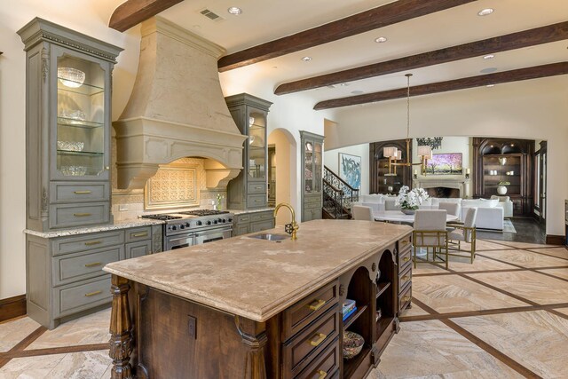 9996 Hollow Way Rd, Dallas, TX 75220 - kitchen with a sink, double oven range, gray cabinetry, inlaid floor details, and beamed ceiling
