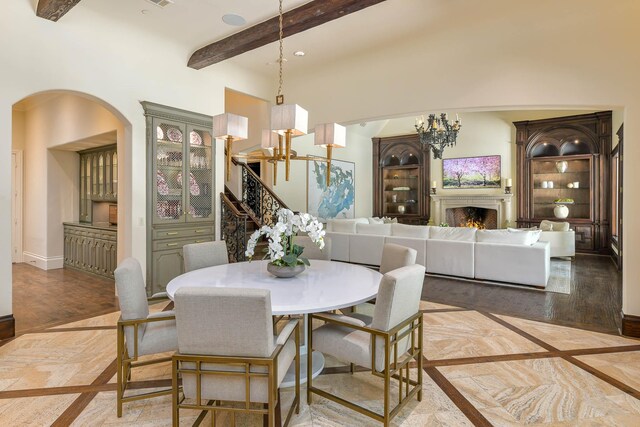 9996 Hollow Way Rd, Dallas, TX 75220 - dining space featuring a chandelier, beam ceiling, a lit fireplace, wood finished floors, and baseboards