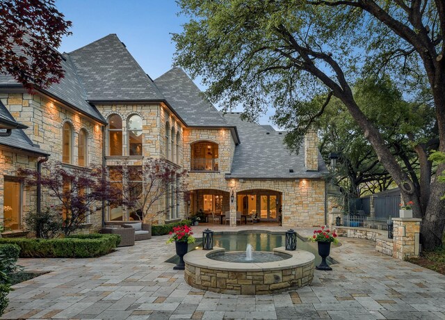 9996 Hollow Way Rd, Dallas, TX 75220 - rear view of property featuring a high end roof, stone siding, and a patio area