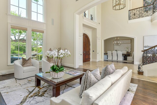 9996 Hollow Way Rd, Dallas, TX 75220 - living room featuring a towering ceiling, a chandelier, wood finished floors, baseboards, and arched walkways