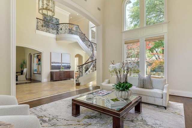 9996 Hollow Way Rd, Dallas, TX 75220 - living room featuring arched walkways, a towering ceiling, hardwood / wood-style flooring, stairway, and baseboards
