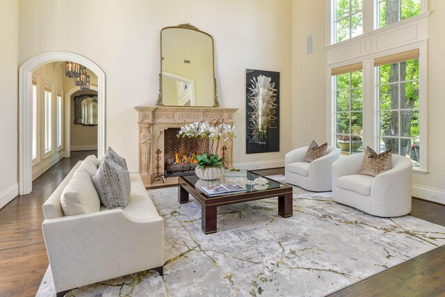 9996 Hollow Way Rd, Dallas, TX 75220 - living area featuring wood finished floors, a high ceiling, baseboards, a high end fireplace, and arched walkways