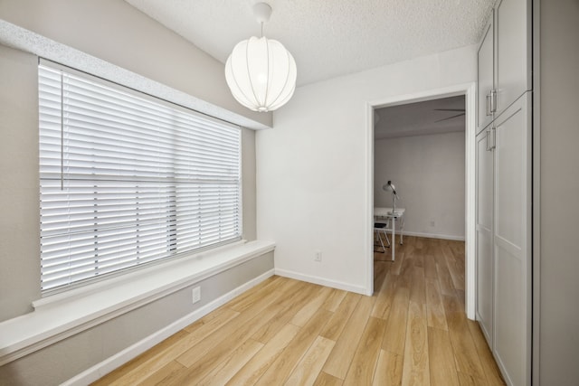 226 E Ridgegate Dr, Garland, TX 75040 - unfurnished dining area featuring light wood finished floors, a textured ceiling, and baseboards