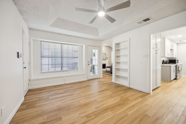 226 E Ridgegate Dr, Garland, TX 75040 - empty room with light wood-type flooring, a textured ceiling, a ceiling fan, baseboards, and built in features