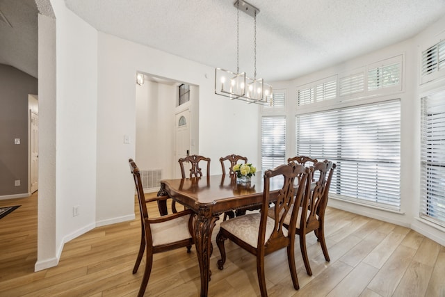 226 E Ridgegate Dr, Garland, TX 75040 - dining space featuring light wood-type flooring, a chandelier, a textured ceiling, and baseboards