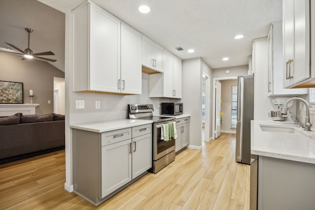 226 E Ridgegate Dr, Garland, TX 75040 - kitchen featuring appliances with stainless steel finishes, a sink, open floor plan, light wood-type flooring, and ceiling fan