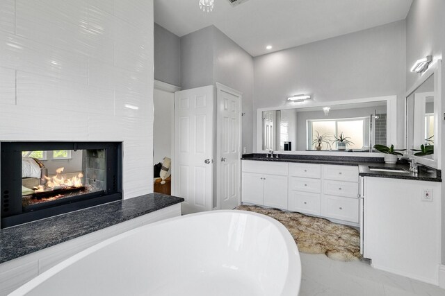 6821 Rochelle Dr, Plano, TX 75023 - bathroom with a freestanding bath, double vanity, marble finish flooring, recessed lighting, and a multi sided fireplace