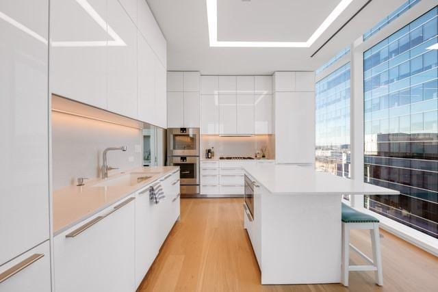 1747 Leonard St Unit 903, Dallas, TX 75201 - kitchen with modern cabinets, a sink, light wood-type flooring, white cabinets, and light countertops