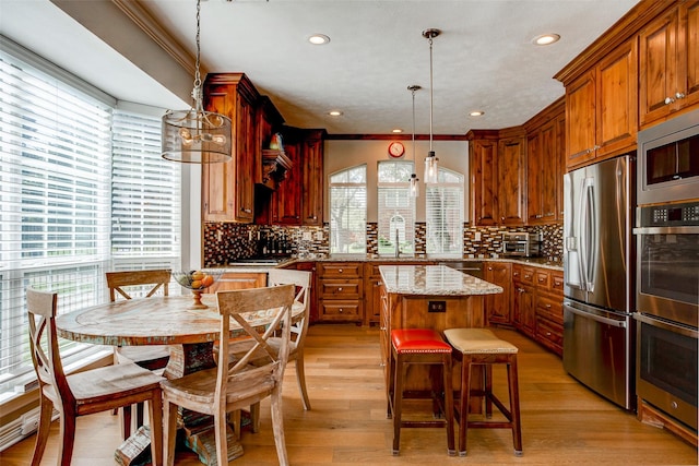 6712 E Park Dr, Fort Worth, TX 76132 - kitchen featuring appliances with stainless steel finishes, a center island, brown cabinets, recessed lighting, and ornamental molding
