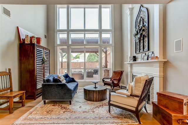 6712 E Park Dr, Fort Worth, TX 76132 - sitting room featuring light wood finished floors, a high ceiling, ornate columns, and a fireplace