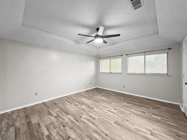 539 Mel Ct, Euless, TX 76039 - empty room with a tray ceiling, a textured ceiling, wood finished floors, a ceiling fan, and baseboards