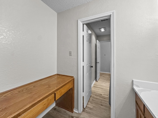 539 Mel Ct, Euless, TX 76039 - corridor with light wood-style floors, a textured ceiling, a textured wall, and baseboards
