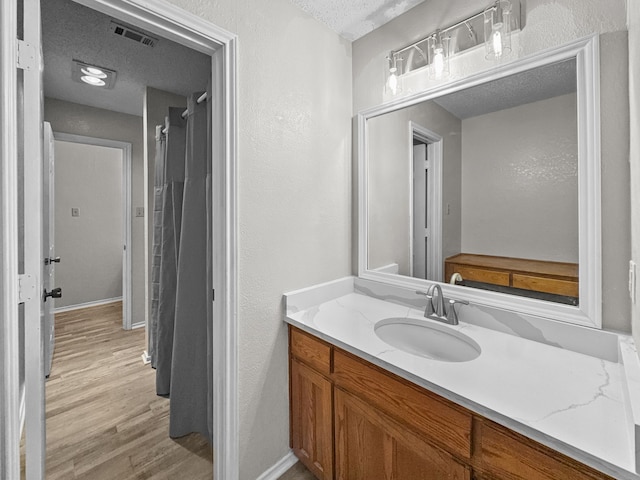 539 Mel Ct, Euless, TX 76039 - bathroom with a textured ceiling, vanity, wood finished floors, a textured wall, and baseboards