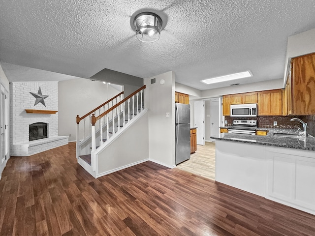539 Mel Ct, Euless, TX 76039 - kitchen with appliances with stainless steel finishes, a sink, open floor plan, wood finished floors, and brown cabinets