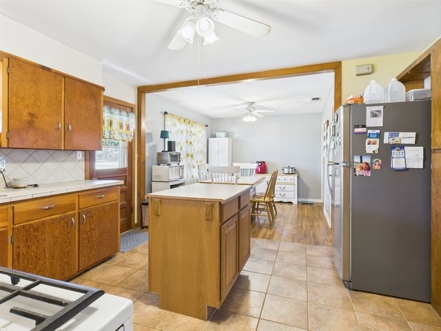 104 Sunny Ln, Athens, TX 75751 - kitchen with freestanding refrigerator, ceiling fan, decorative backsplash, and brown cabinets