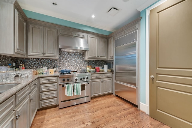 3505 Turtle Creek Blvd Unit 3G, Dallas, TX 75219 - kitchen with high end appliances, extractor fan, light wood finished floors, backsplash, and ornamental molding