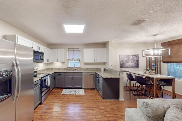 1211 Leeward Ln, Wylie, TX 75098 - kitchen with appliances with stainless steel finishes, a sink, a peninsula, white cabinetry, and light wood-style floors